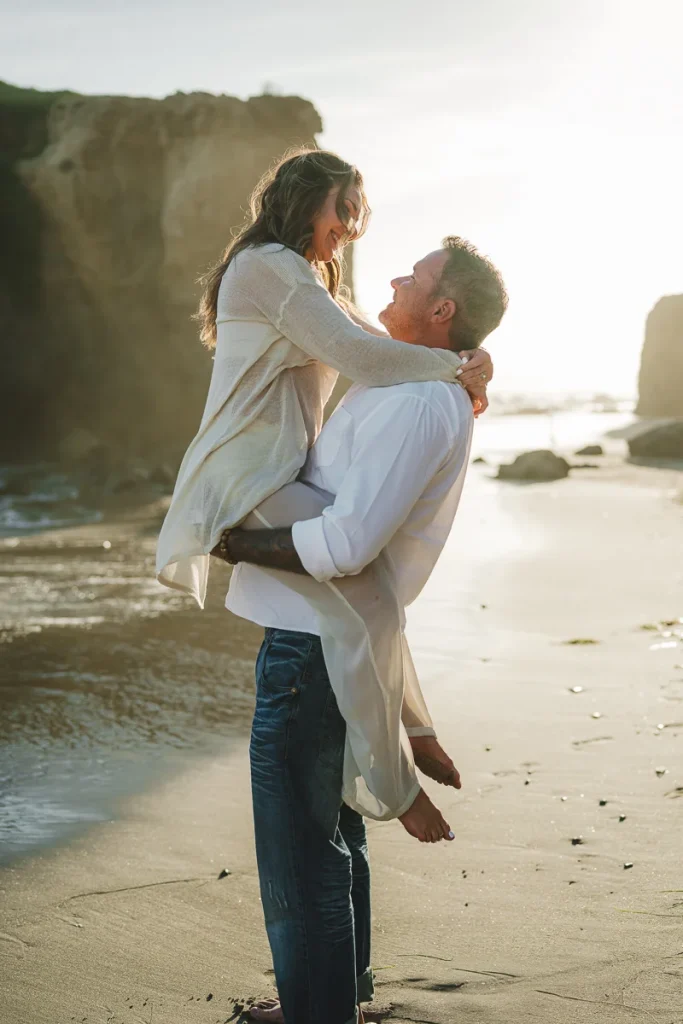 Engaged couple embracing at the beach during sunset