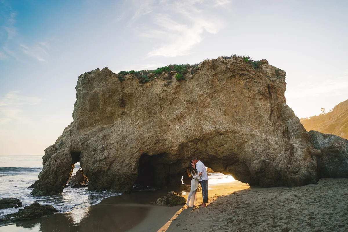 Engaged Couple kissing at rock at El Matador Beach at Sunset