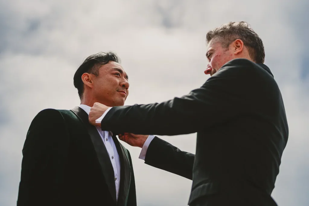 Bestman helping groom adjust his bowtie